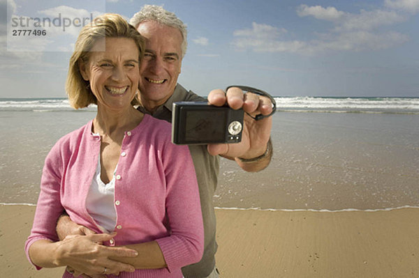 Paar beim Fotografieren am Strand