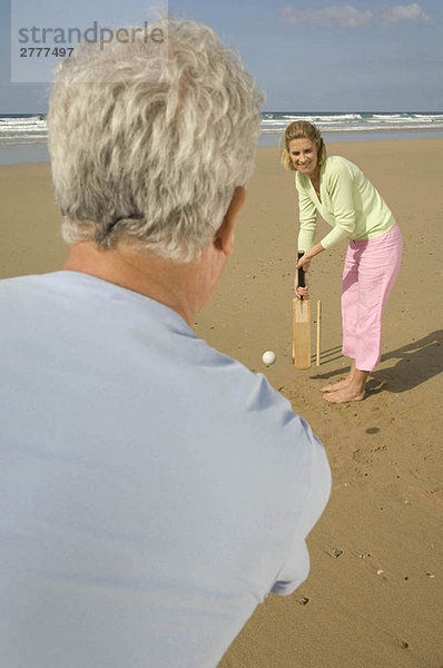 Paar spielt Cricket am Strand