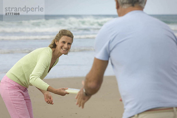 Paar spielt Frisbee am Strand