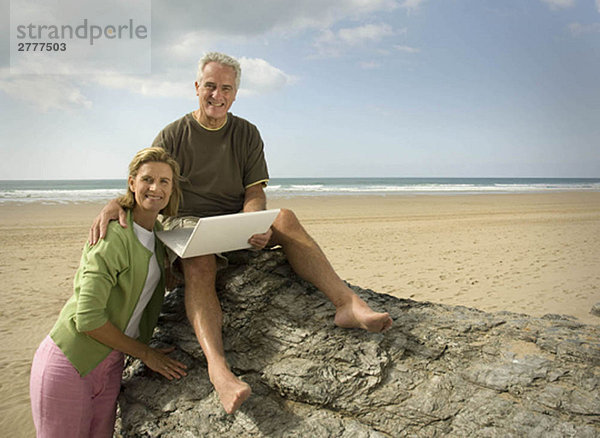 Paar am Strand mit Laptop-Computer