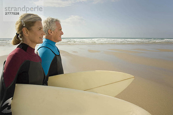 Paar mit Surfbrettern am Strand