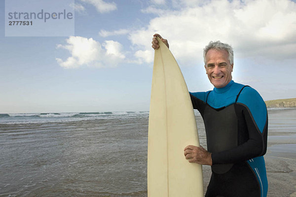 Mann mit Surfbrett am Strand