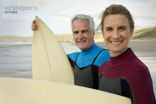 Paar mit Surfbrettern am Strand