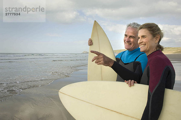 Paar mit Surfbrettern am Strand