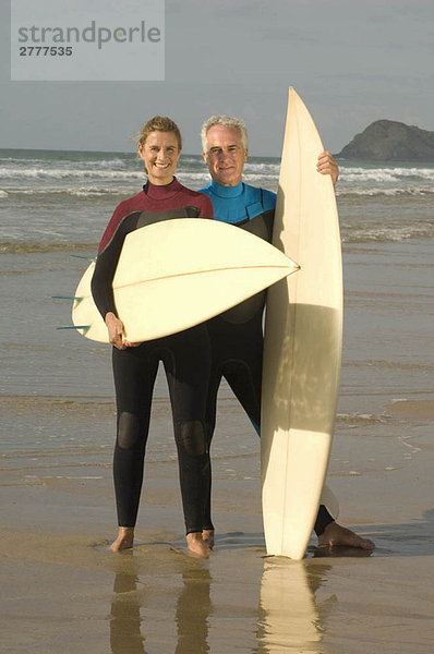 Paar mit Surfbrettern am Strand