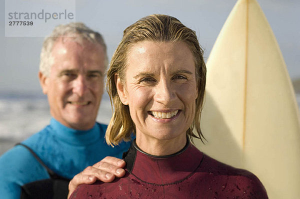 Paar in Neoprenanzügen am Strand