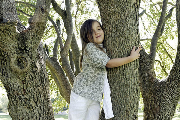 5 Jahre altes Mädchen an einem Baum stehend