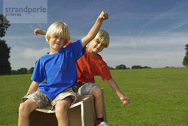 Jungen auf einer Kiste  Arme ausstrecken