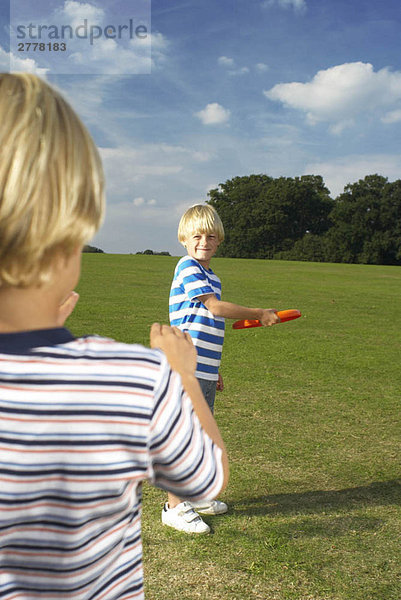 Junge wirft Frisbee zu einem anderen Jungen