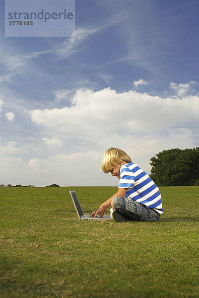 Junge am Computer im Feld