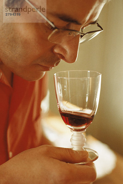 Mann riecht Rotwein im Weinglas