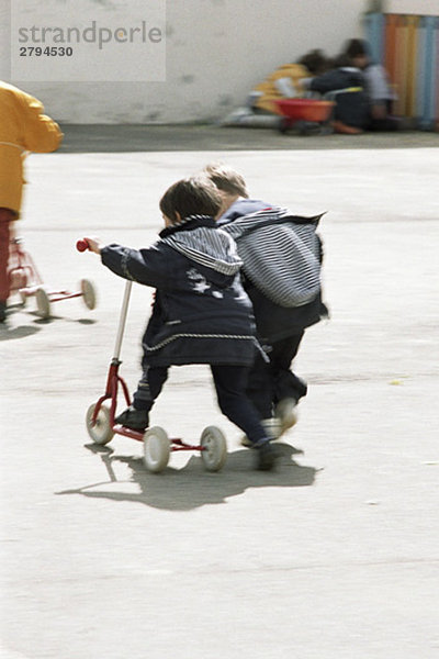 Kinder laufen mit Rollern  Rückansicht