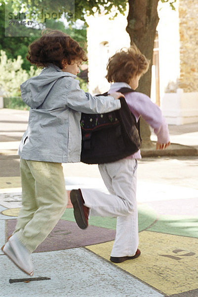 Kleine Mädchen  die zusammen Hopscotch spielen.