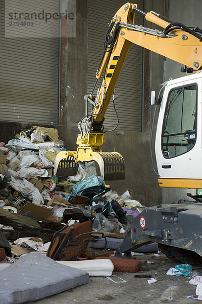 Erdbewegungsmaschine  die Müll von einem großen Haufen aufnimmt.