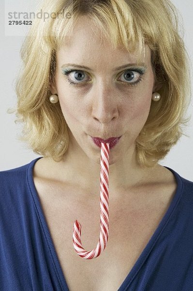 Blonde Frau mit einer Zuckerstange im Mund