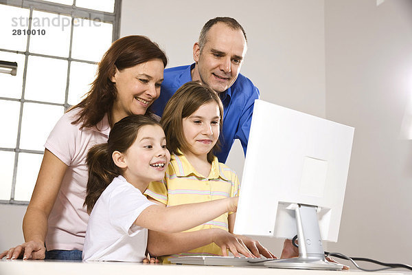Familie lächelnd beim auf Computer-Bildschirm ansehen