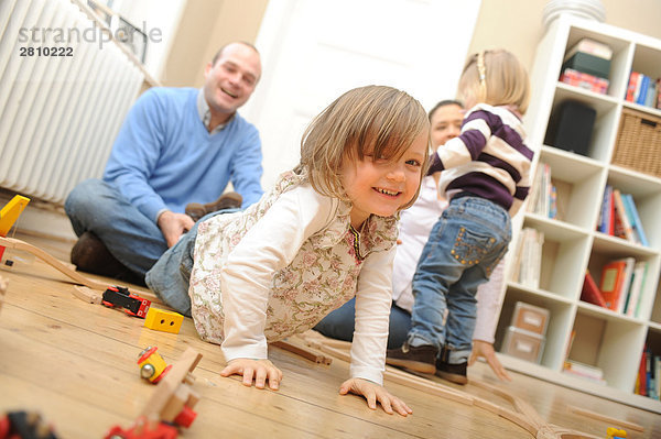 Mädchen mit Spielzeug und ihrem Vater zieht spielerisch ihr spielen