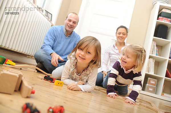 Mädchen mit Spielzeug und ihrem Vater zieht spielerisch ihr spielen