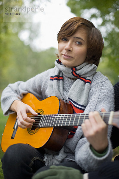 junge Frau junge Frauen Garten Gitarre spielen