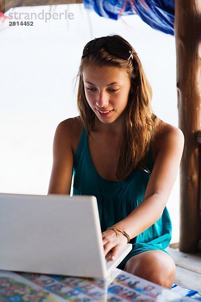 Eine skandinavische Teenagerin mit einem Laptop am Meer Thailand.