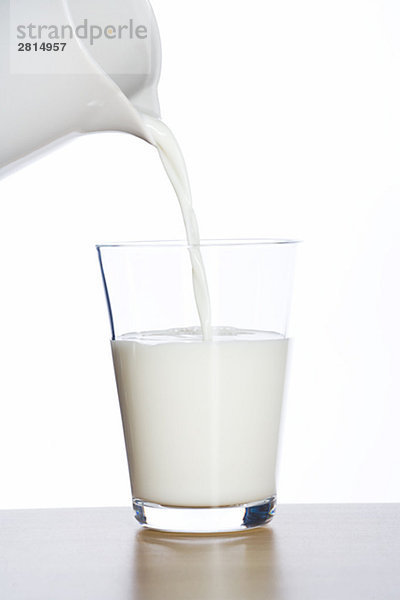 Milch wird in ein Glas gegossener.