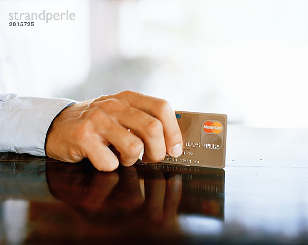 Die Hand eines Mannes halten eine Kreditkarte.