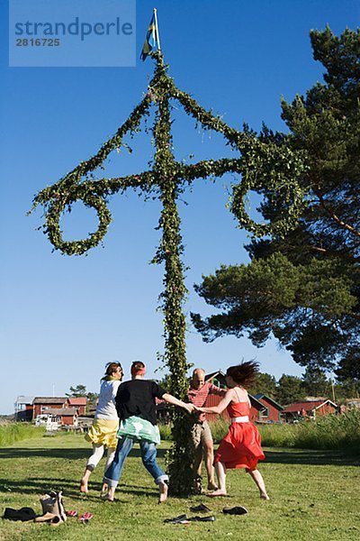 Menschen tanzen um den Midsommarbaum für Midsummer Schweden.