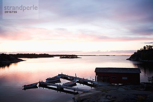 Ein Bootshaus in den Sonnenuntergang in den Schären von Stockholm Schweden.