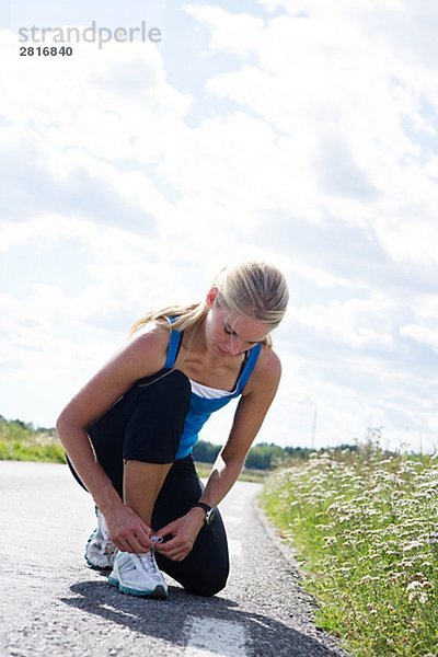 Eine Frau ihrem Schnürsenkel Schweden zu befestigen.