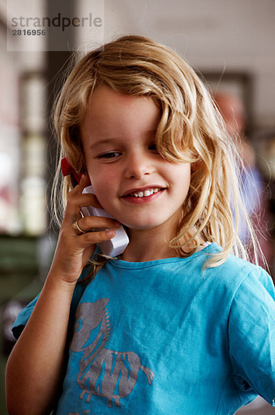 Ein Mädchen mit einem Mobiltelefon Dänemark spielt.