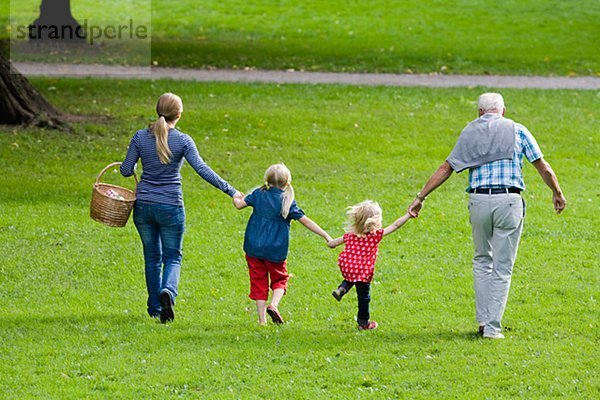 älterer Mann Frau und Kinder gehen für ein Picknick im Park Schweden.