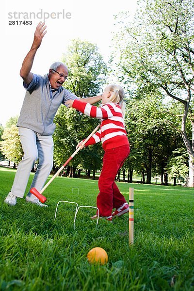 Mädchen und älterer Mann spielen Krocket im Park Schweden.