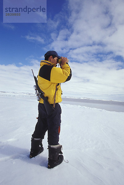 Young Inuit Hunter scannt Horizont am Eis Flow Rand nahe Dorf von Kimmirut  Baffin Island  Nunavut  Kanada.