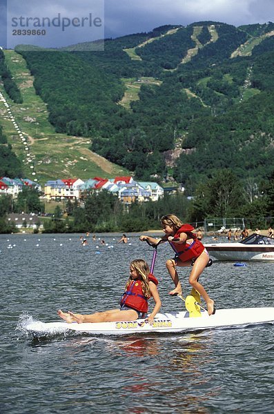 Zwei junge Mädchen spielen auf Surf-Bike' am Lac Tremblant  Mont Tremblant Resort  nördlich von Montreal  Québec  Kanada.