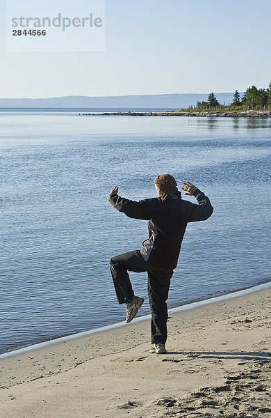 Person üben Tai-Chi in den frühen Morgenstunden am Cap-Aux-Oies Strand in Charlevoix  Québec  Kanada