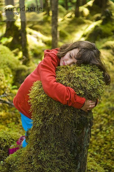 Mädchen knuddeln Moss abgedeckt Stump  Naikoon Provincial Park  Queen Charlotte Islands  British Columbia  Kanada