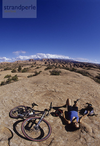 Ein Mountainbiker mit Abit des Respite  Einweichen in der Sonne auf den glatten Felsen in Moab  Utah  USA.