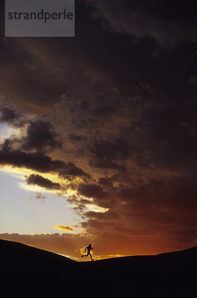 Ein Silhoette ein Läufer auf dem R??cken drop lebendige Sonnenuntergang  Moab  Utah  USA.