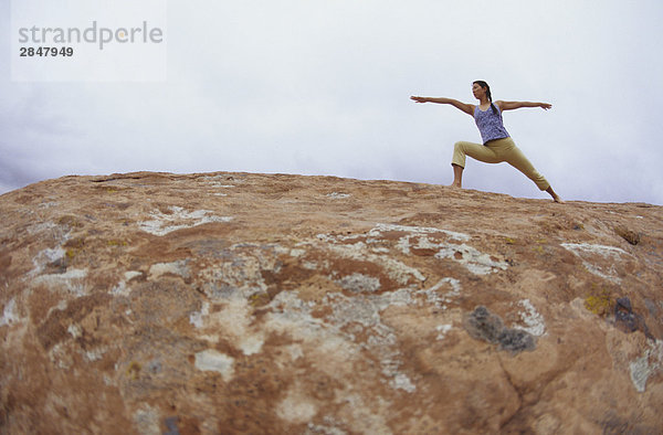 Ein young Frau macht Yoga auf den roten Felsen in Moab  Utah  USA
