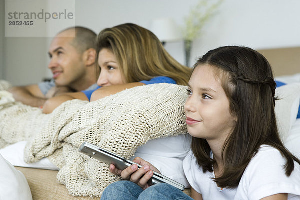 Familie beim gemeinsamen Fernsehen  Mädchen mit Fernbedienung