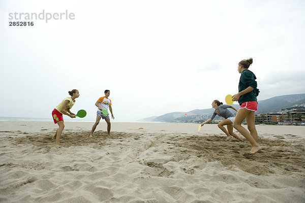 Teenager-Freunde spielen Paddleball am Strand