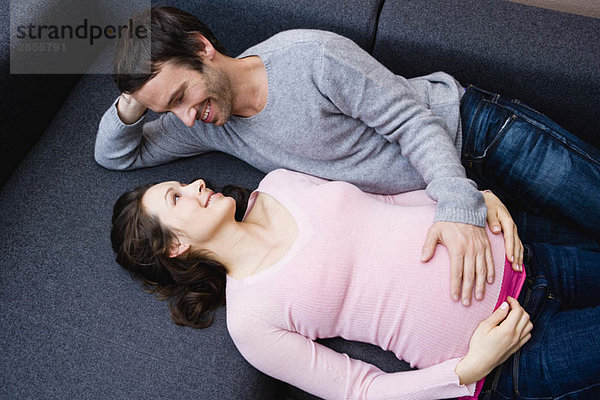 Schwangere Frau und Mann auf der Couch liegend