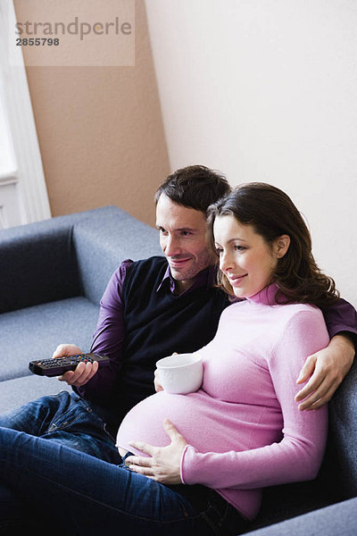 Schwangere Frau und Mann auf der Couch sitzend