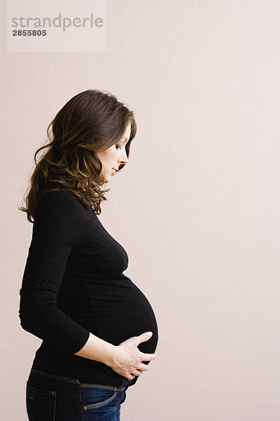 Eine schwangere Frau schaut auf ihren Bauch.