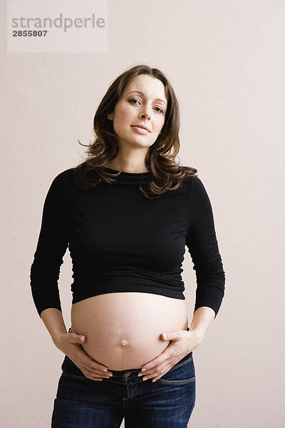 Schwangere Frau  die ihren Bauch hält.