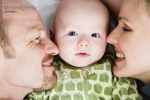 Baby liegt zwischen Vater und Mutter