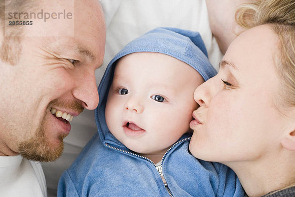 Baby liegt zwischen Vater und Mutter