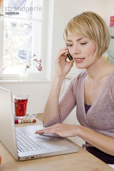 Frau am Tisch beim Telefonieren