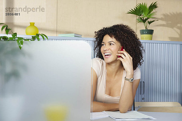 Junge Frau am Telefon am Schreibtisch im Büro