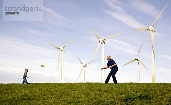 Mann  Junge spielt Frisbee bei Windkraftanlagen